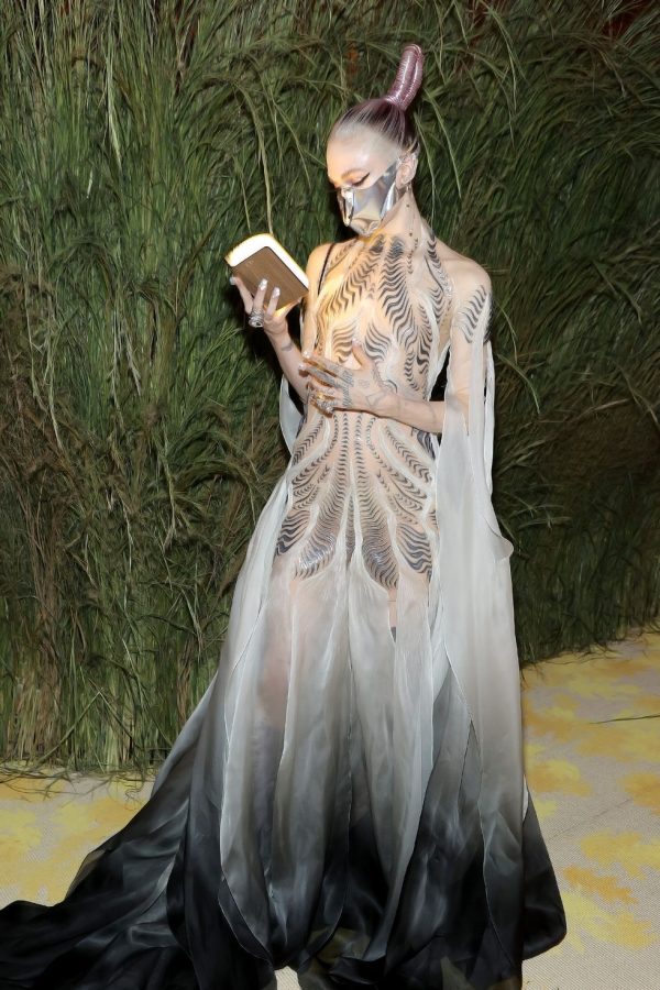Claire Boucher, more commonly known as the experimental musician Grimes, arrived at the Met Gala in Iris van Herpen’s custom “Bene Gesserit” gown, which took more than 900 hours of construction. Each metallic swoosh and inch of fabric was first hand-cast from liquid silicone before being meticulously placed in between 26 layers of hand-sewn and dyed silk. The futuristic and other-worldly feeling radiating off of this outfit is meant to reference the 1965 science-fiction novel by Frank Herbert, Dune, which is currently being transformed into a movie adaptation. Collaborating with the staff on the Dune production, Grimes also wore the original metallic mask from the film as well as accompanying the look with a real metallic sword that was inspired by a western European sword from around the 1400s. Lastly, Grimes completed the look with metal elven ears, hand-crafted by Lillian Shalom. 