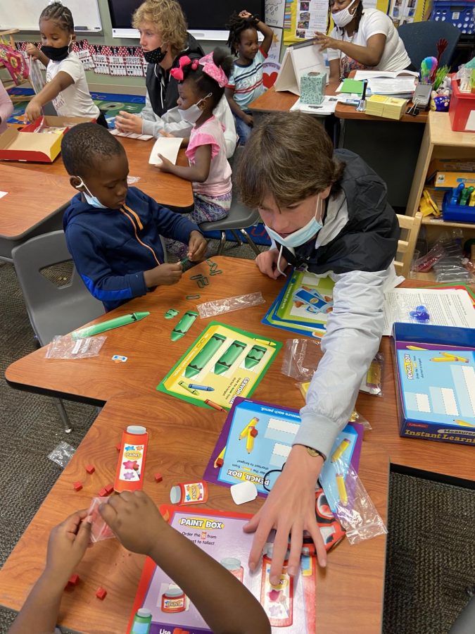 (Above) Students from leadership would typically assist teachers at Ivey Lane and interact with the school’s students in small groups by helping them complete academic hands-on activities. Alec Bankston, grade 11, helps children in his group complete a fun measuring activity. Working in this environment helps Highlanders practice interpersonal communication skills from these new experiences. 