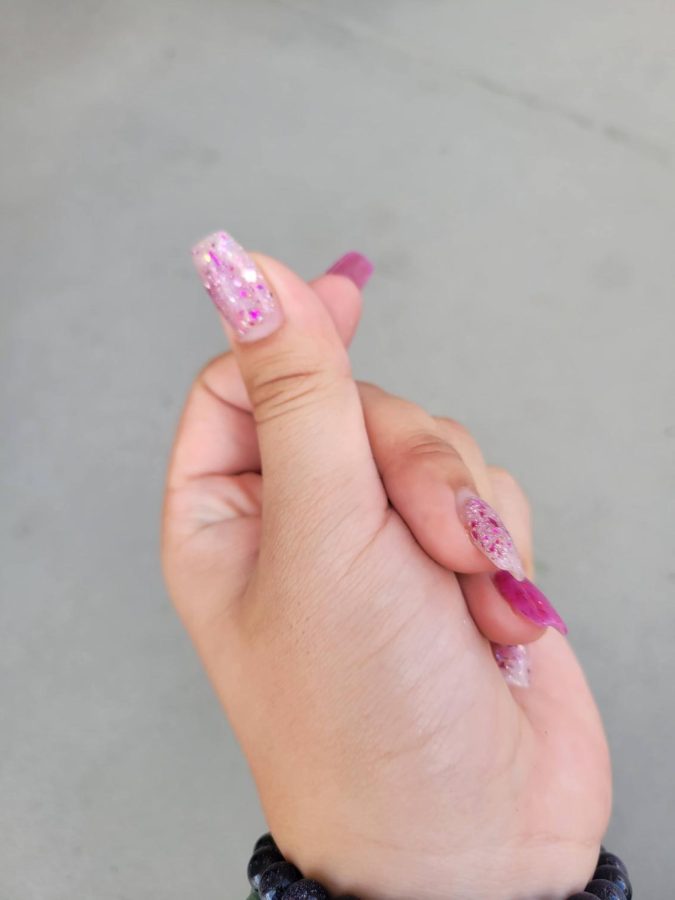 (Above) Miya Okuda, grade 12, shares how she’s recently been doing two-shades on her nails. Her go-to nails are a shade of pink or blue, and anything with sparkles. This set reminded her of cherry blossoms, and she described them as, “Bright, sparkly, and fun,” adding how they reflect her personality. She would love to try storyboard nails and believes nails are really important because they, “Are one of the first things people will notice about you, especially when shaking your hand or when you’re moving.” When someone has nails as strong as these, they certainly are a great point of conversation indeed. All photos by Serena Young. 
