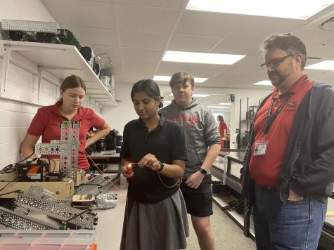 (Above) Mr. Jim Varley, who works at Lockheed Martin and is a Hazmat men-
tor, is an expert in design processes and has been paramount to the success of

Hazmat Robotics. He assists (left to right) Julia Nicholson, grade 12; Raheema
Naseeruddin, grade 12; and Garrett Thorn, grade 10, prior to going to States. All

photos by Anthony George.