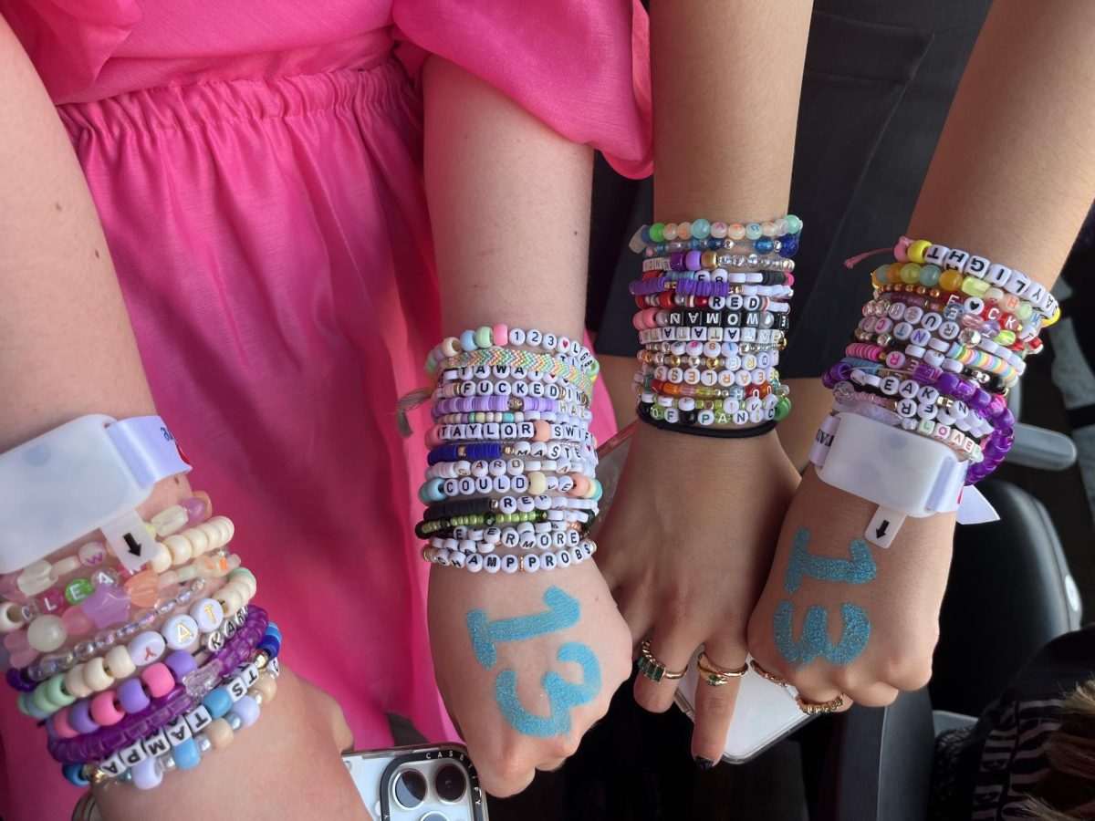 (Above) The fan project that has dominated the Eras’ Tour has been trading friendship bracelets, which is inspired by the lyric, “So make the friendship bracelets, take the moment and taste it” from the song, “You’re On Your Own Kid” on Swift’s newest album, Midnights. Fans, such as Kathryn Hudson, grade 11, and Isa Tapia Arocho, grade 11, pictured here, traded before and after the show (or in a McDonald’s
like the transaction I saw prior to the doors opening). Another thing that was featured on most fans’ hands was the number 13. This comes from Swift’s affinity for the number as she was born on December 13. In an interview with MTV back in 2009, Taylor Swift explained why she always draws the number on her hand before a show, noting, “I was born on the 13th. I turned 13 on Friday the 13th. My first album went gold in 13 weeks. My first #1 song had a 13-second intro.”