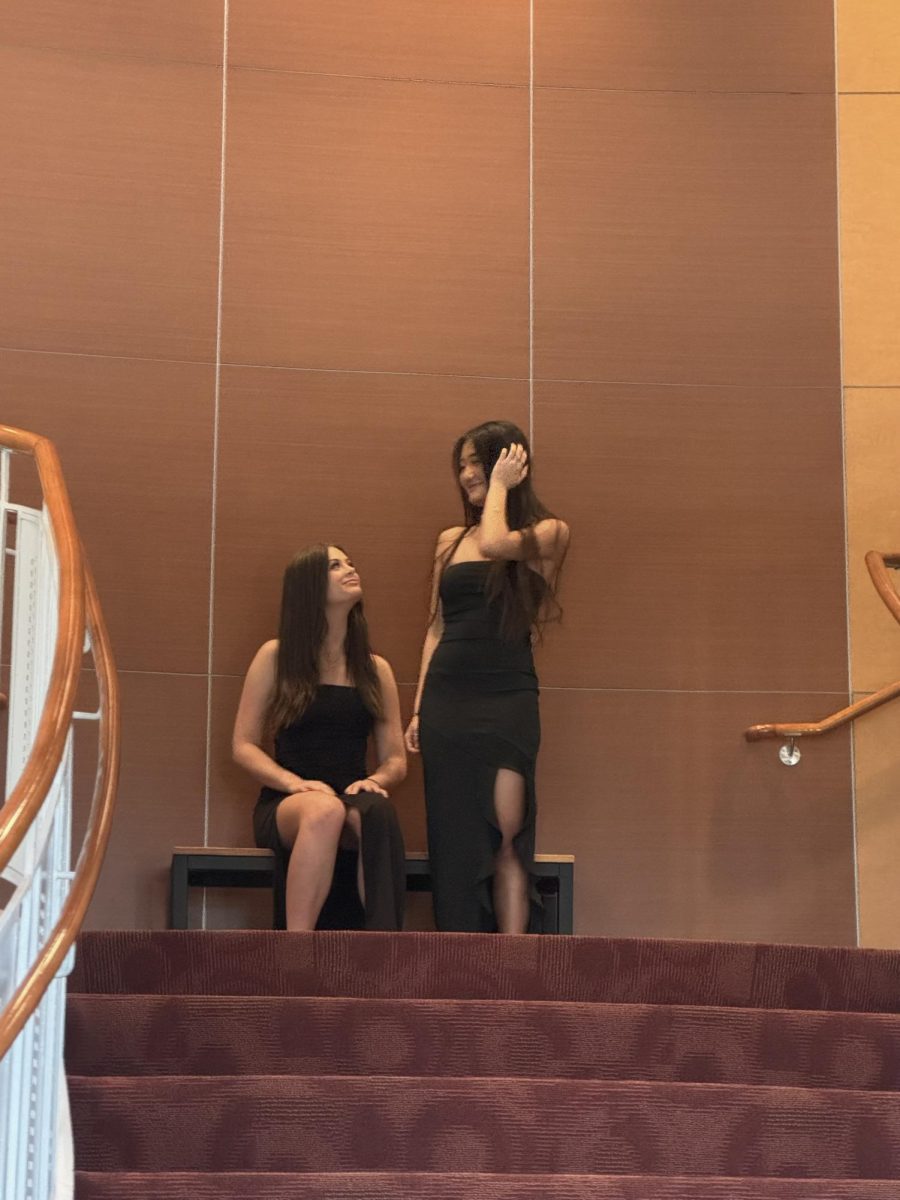 (Above) Emily Sacco and Ashley Taddeo, both grade 11, match each other with a classic slim, black dress with a slit on one side.