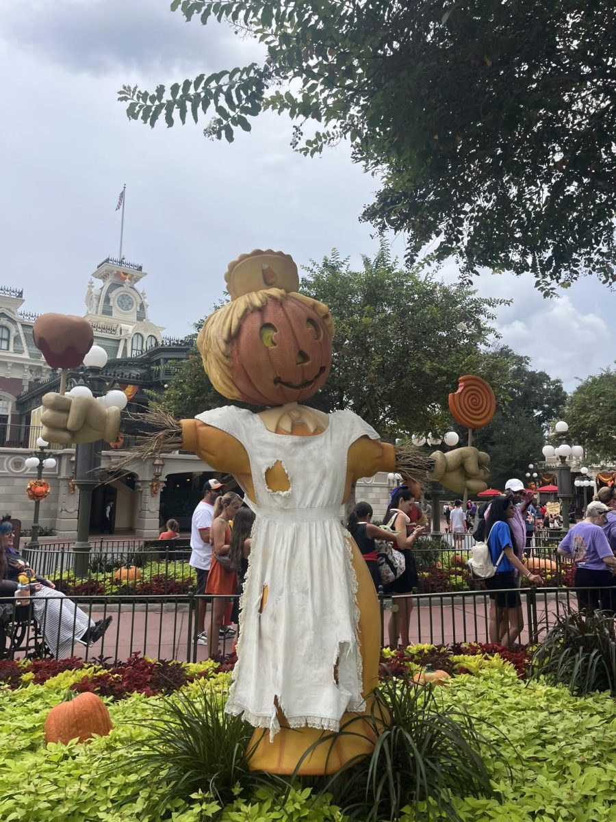 (Above) This festive pumpkin-headed scarecrow greets guests as they enter Magic Kingdom, dressed in fall-themed attire perfect for the season. Decorations like these set the spooky tone and the Halloween-like atmosphere. 