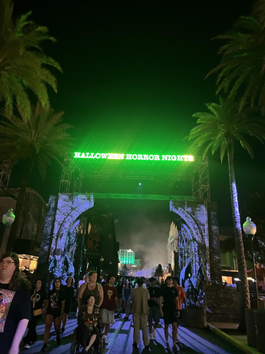 (Above) The entrance sign of Halloween Horror Nights beckoned guests to enter its hallowed halls for years, and in the year of 2025, now flashes neon green instead of the traditional blue sign. This was a deliberate design choice to fit this year’s theme for the 34th Halloween Horror Nights. Many people noted this change and were pleased by this electrifying surprise. The change of lighting added to the suspense of entering the gates and blended with an element of the unknown. A foggy welcome awaits those who enter. 