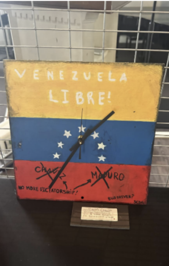 (Above) Sarah Coehlo, grade 9, created this piece of artwork last year for an art project. The design features a clock with Venezuela’s flag in the background.
Venezuela libre is presented proudly at the top of the artwork, while Hugo Chávez Frías, and Nicolás Maduro Moros are clearly shown to be crossed out.