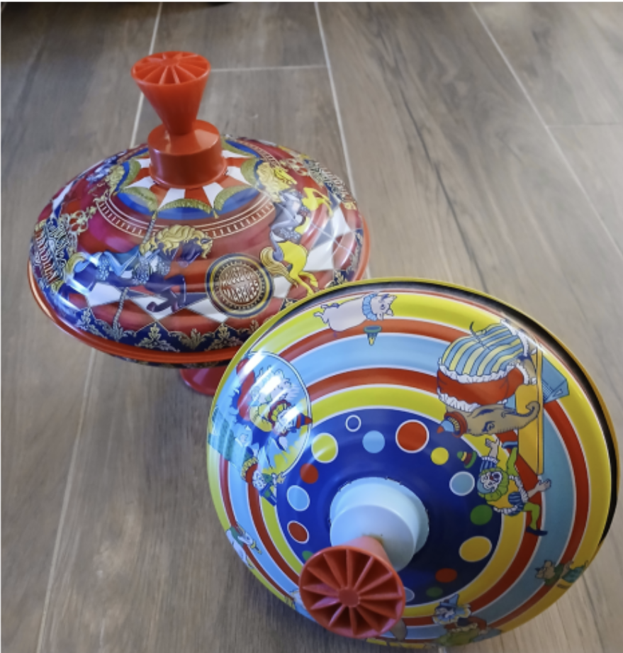 (Above) These are what Schylling toys looked like prior to the addition of Needohs. The circus themed vintage metal spinning top was once a popular traditional toy. Ms. Ginger Bryant collects tin toys with circus patterns and carousels that give a visually appealing effect when spun.